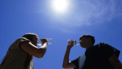 Dos personas se hidratan con agua durante en un día caluroso. El Clima en RD estará dominado por la incidenica de una vaguada la cual provocará aguaceros en algunas provincias.